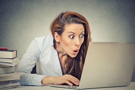 Young business woman looking at her laptop computer screen happy surprised face expression emotion feelings Young business woman looking at her laptop computer screen happy surprised face expression emotion feelings